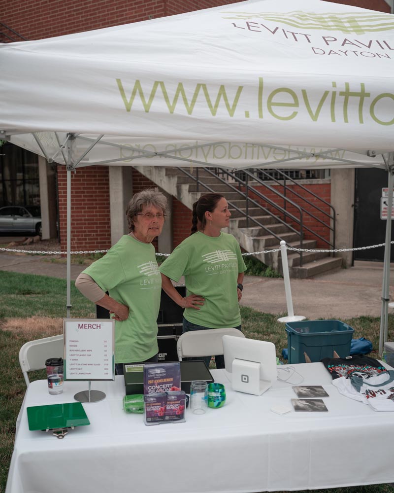 Levitt Pavilion volunteer sitting at merchandise table helping guests
